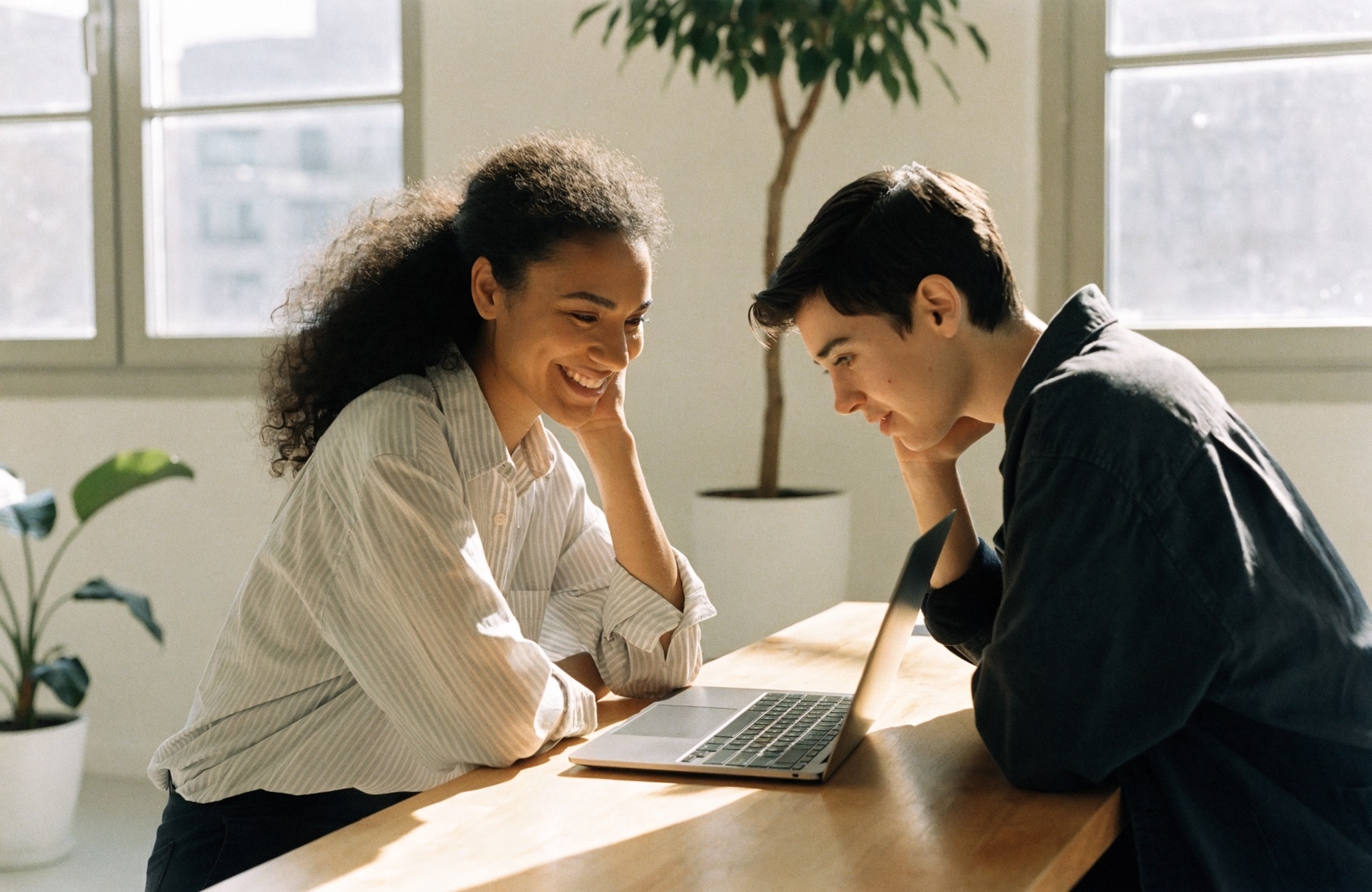 A coach and a client looking at a laptop together.